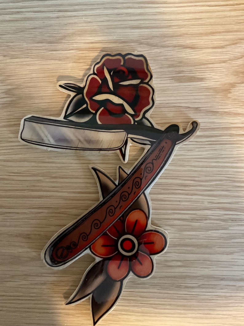 May include: A wooden cutout of a traditional tattoo design featuring a red rose and a straight razor with a decorative handle.