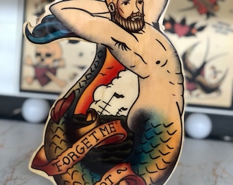 May include: A wooden cutout of a merman with a beard and a blue and green tail. The merman is holding his tail and has a banner that says "Forget Me Not".
