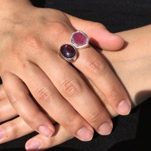 May include: A silver ring with two pink gemstones. The larger gemstone is hexagonal and the smaller gemstone is oval.