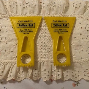 May include: Two yellow plastic ice scrapers with the text "Call 584-2121 Yellow Cab Over 100 Years Faithful Courteous Service" printed on them.