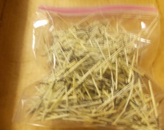 May include: A clear plastic resealable bag filled with a collection of thin, sharp, needle-like quills. The quills are primarily off-white and cream in color, featuring distinct dark brown and black tapered tips and variegated dark markings throughout.