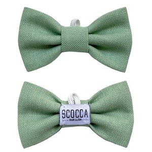 Può includere: Due papillon verdi, uno con un'etichetta bianca che recita "SCOCCA - PAPILLON -"
