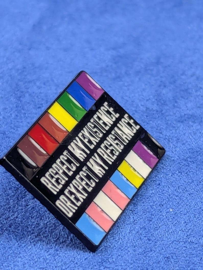 May include: A square enamel pin with a black border and the text "RESPECT MY EXISTENCE OR EXPECT MY RESISTANCE" in white. The pin features a rainbow design and other pride flag colors.