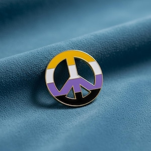Puede incluir: Un pin esmaltado circular con el símbolo de la paz. El diseño está dividido en cuatro franjas horizontales de colores amarillo, blanco, morado y negro, encerradas dentro de un fino borde de metal dorado que perfila la forma circular.
