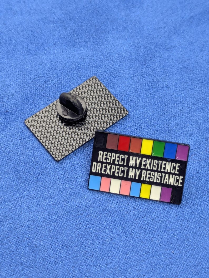 May include: A rectangular enamel pin with the text "RESPECT MY EXISTENCE OR EXPECT MY RESISTANCE" in white. The pin features a rainbow color scheme and a black backing with a pin clasp.