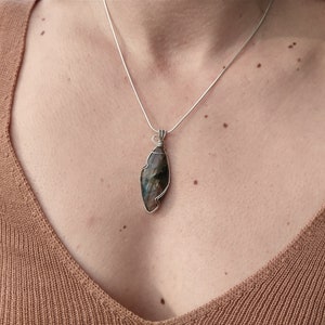 May include: A silver chain necklace with a silver wire wrapped iridescent labradorite pendant.