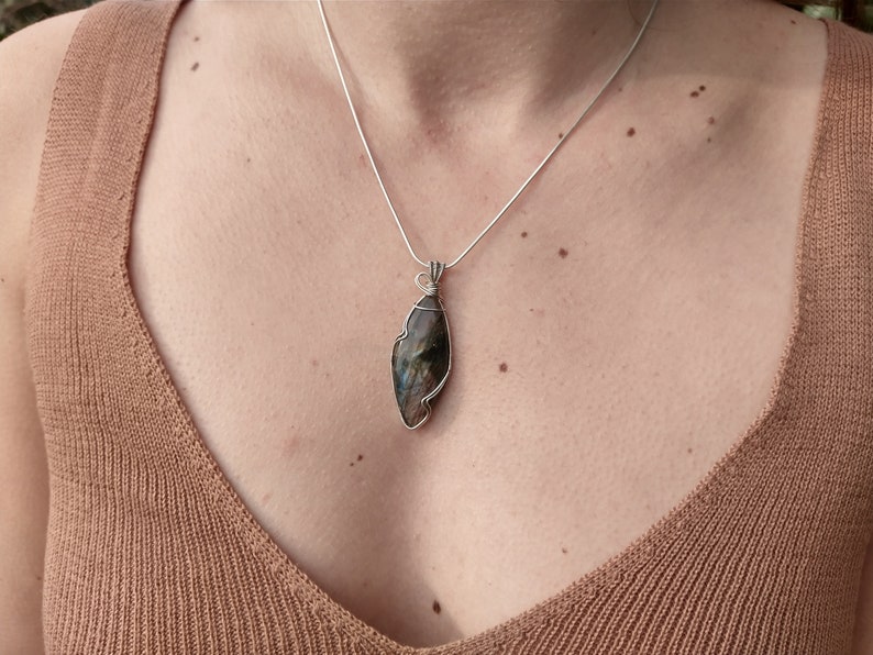 May include: A silver chain necklace with a silver wire wrapped iridescent labradorite pendant.