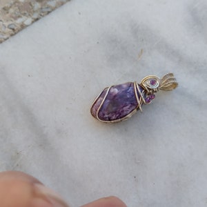 May include: A purple and silver wire-wrapped pendant with small pink gemstones.