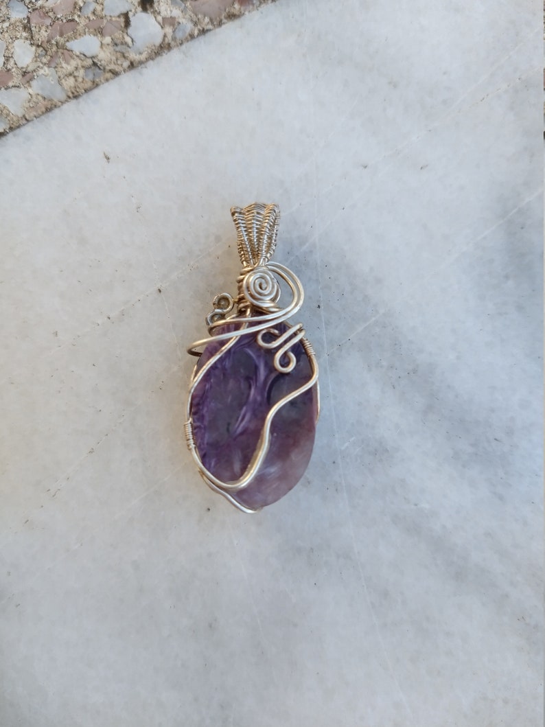May include: A purple amethyst stone wrapped in silver wire, forming a pendant.
