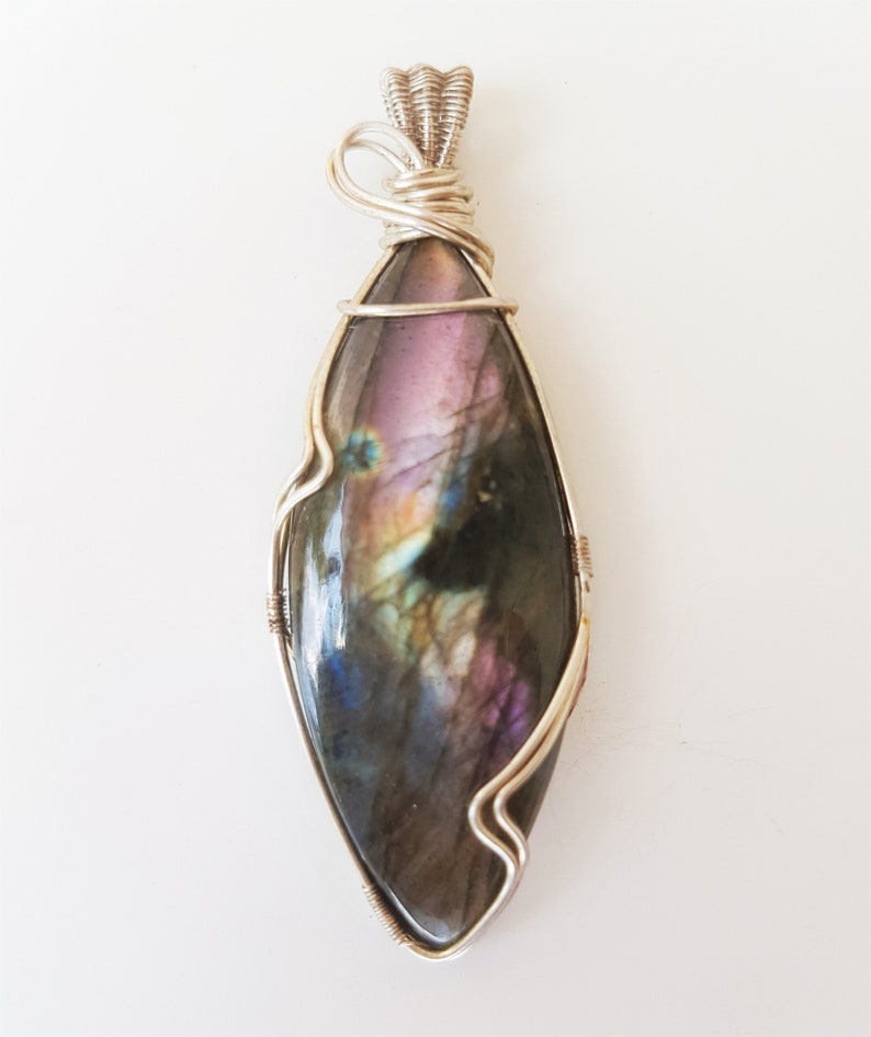 May include: A silver wire wrapped pendant featuring a large iridescent labradorite gemstone with shades of purple, blue, and green.