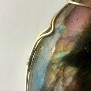 May include: A silver wire wrapped pendant featuring a large iridescent labradorite gemstone with shades of blue, green, and brown.