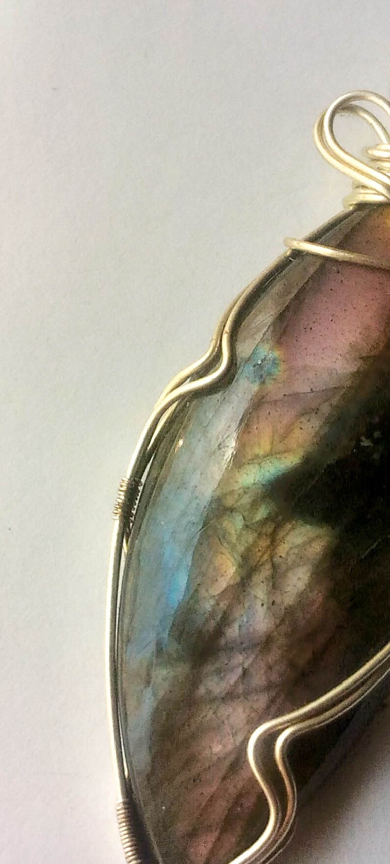 May include: A silver wire wrapped pendant featuring a large iridescent labradorite gemstone with shades of blue, green, and brown.