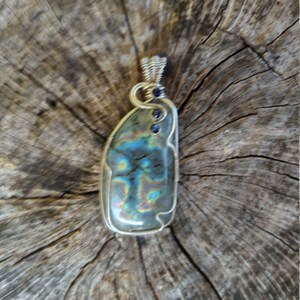 May include: A silver wire wrapped pendant featuring a iridescent labradorite gemstone with blue accents.