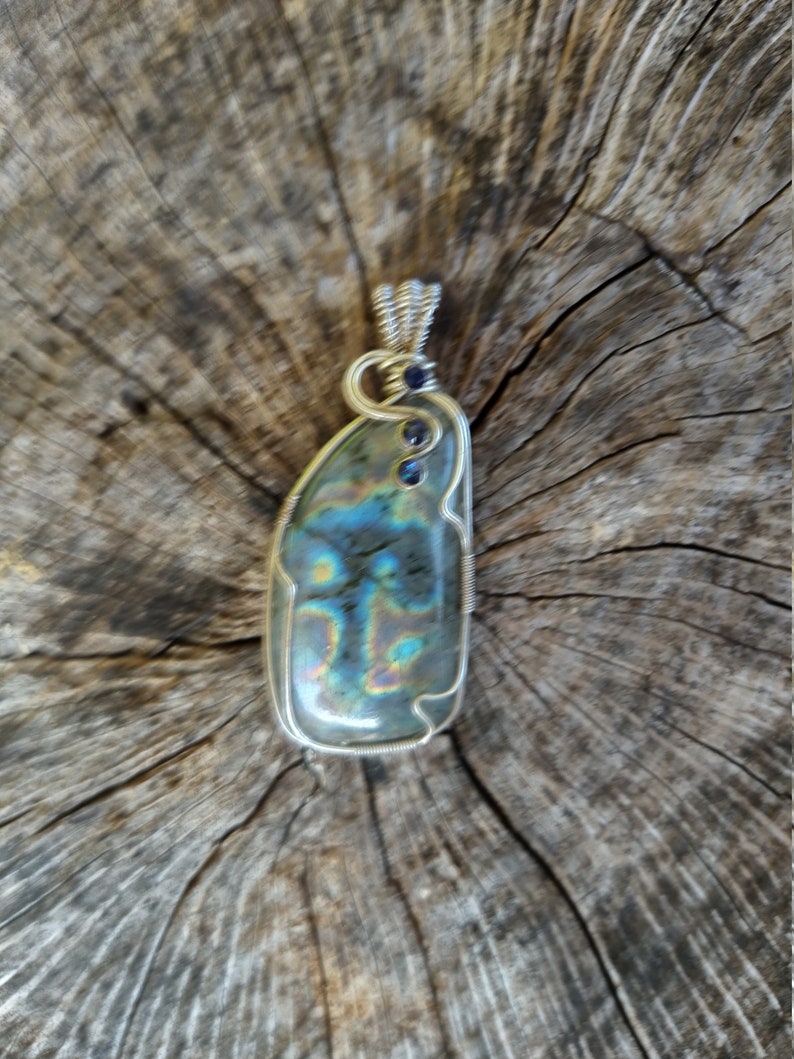 May include: A silver wire wrapped pendant featuring a iridescent labradorite gemstone with blue accents.