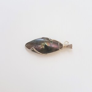 May include: A silver wire wrapped pendant featuring a dark iridescent labradorite gemstone.