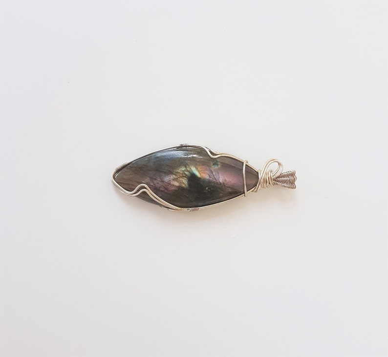 May include: A silver wire wrapped pendant featuring a dark iridescent labradorite gemstone.