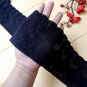 May include: Black lace trim with a floral design. The lace is delicate and intricate, with a scalloped edge.