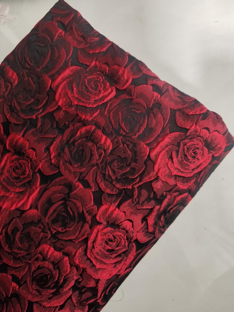 May include: Red and black fabric with a rose pattern. The fabric is textured and has a raised design.