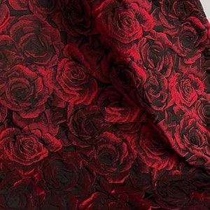 May include: Red fabric with a raised rose pattern. The roses are a deep red colour and are arranged in a repeating pattern.