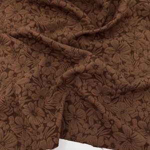 Puede incluir: Tela marrón con un patrón floral en relieve. La tela tiene una textura casi aterciopelada.