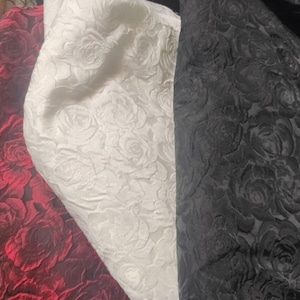 May include: Three fabric swatches with an embossed rose pattern. The swatches are red, white, and black.