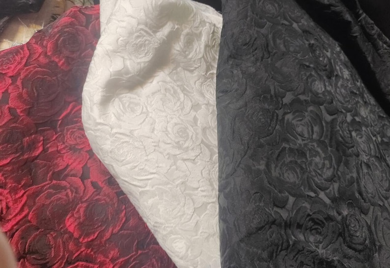 May include: Three fabric swatches with an embossed rose pattern. The swatches are red, white, and black.