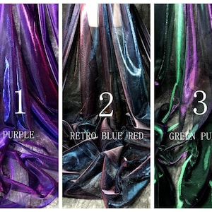 May include: Three swatches of iridescent fabric in different color combinations. The first swatch is purple and red, the second is blue, red, and black, and the third is green and purple.