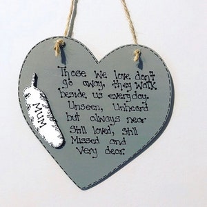 Könnte beinhalten: Ein graues, herzförmiges Schild aus Holz mit einer weißen Feder und dem Text "Those We love don't go away, they walk beside us everyday. Unseen, Unheard but always near Still loved, Still Missed and Very dear. MUM"