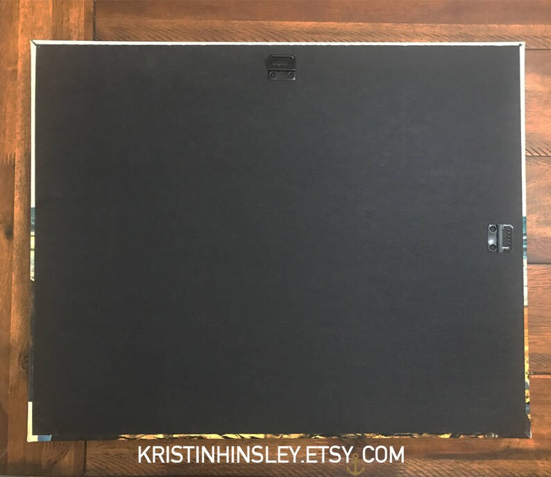 May include: A black canvas print with a white border and two metal hanging clips on the back. The print is blank and ready for a custom design.