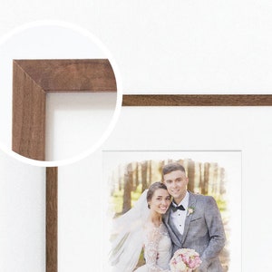 May include: A framed watercolor painting of a couple in a forest setting. The couple is dressed in wedding attire and is smiling. The frame is brown wood with a white mat.