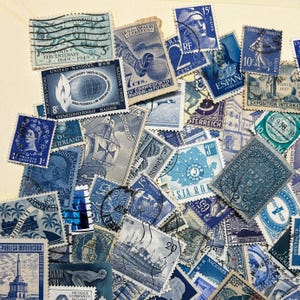 May include: A collection of vintage postage stamps in various shades of blue. The stamps feature diverse designs, including portraits, ships, and historical landmarks. Some stamps have text in multiple languages, and the collection is arranged on a light background.