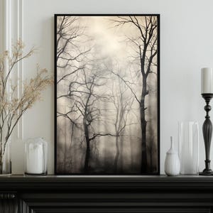Könnte beinhalten: Ein gerahmter Kunstdruck, der eine neblige Waldszene zeigt. Das Schwarz-Weiß-Foto zeigt kahle Bäume im Nebel, wodurch eine stimmungsvolle Landschaft entsteht. Das Kunstwerk wird auf einem schwarzen Kaminsims ausgestellt.