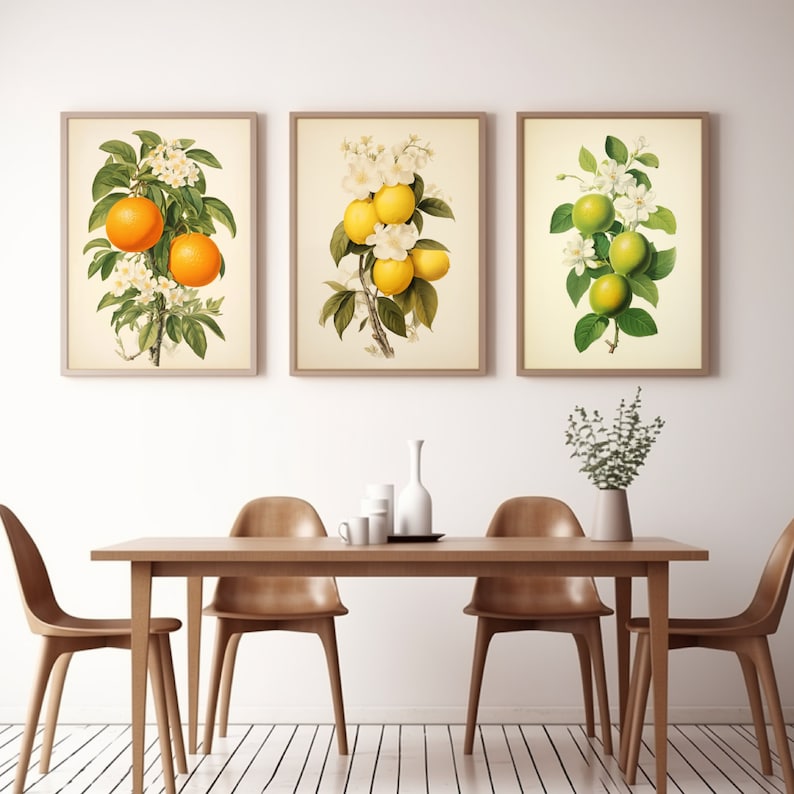 May include: Three framed botanical prints featuring citrus fruit branches with white blossoms and green leaves. The prints are displayed on a white wall above a wooden table with chairs.