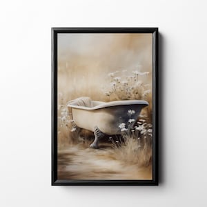 Puede incluir: Una impresión artística enmarcada representa una bañera antigua con patas de garra en un campo de hierba alta y flores silvestres blancas. La bañera es blanquecina con detalles grises, y una toalla doblada descansa en el borde. La obra tiene una estética suave y soñadora.