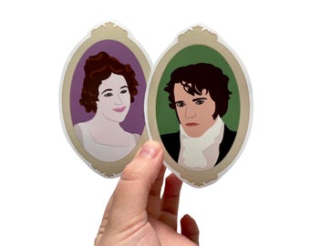 May include: Two oval-shaped stickers with gold frames. The stickers feature portraits of a woman and a man. The woman has brown hair and is wearing a white dress. The man has brown hair and is wearing a white shirt and a black jacket. The background of the woman's portrait is purple, and the background of the man's portrait is green.