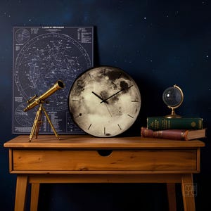 May include: A round wall clock featuring a detailed photographic print of the moon's surface as the dial, with thin black hour markers and black hands. The clock is positioned on a wooden surface alongside a brass telescope and books.