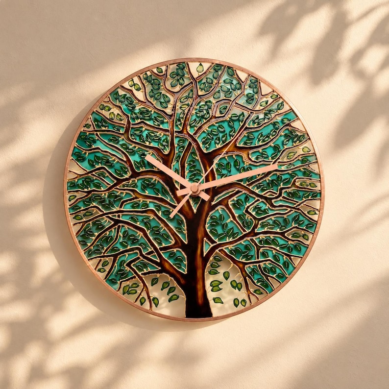 Hand-painted Tree of Life glass wall clock with turquoise and green foliage, copper-colored branches and hands, displayed on a warm beige wall with soft natural sunlight and leafy shadows.