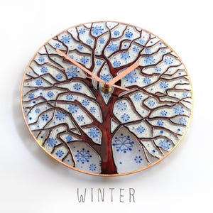 Winter Tree of Life wall clock with snowy branches, handcrafted glass artwork inspired by nature and changing seasons