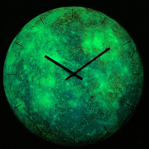 May include: A green glow-in-the-dark clock with black hands, resembling the surface of the moon.
