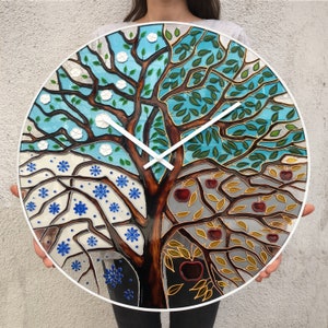 Hand-painted 24-inch glass wall clock depicting the four seasons in one tree design. This oversized clock adds a modern touch to any space, offering a functional yet artistic piece for large walls in your home or office.