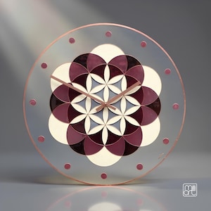 May include: A circular wall clock with a transparent face featuring a central geometric flower of life pattern in shades of deep plum and cream. The clock has a thin copper-coloured frame, matching copper hands, and small circular hour markers.