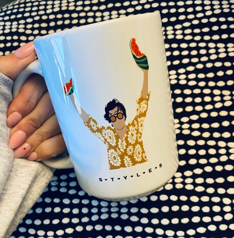 May include: White ceramic mug with a graphic of a person wearing a yellow floral shirt and holding watermelon slices. The text "STYLES" is printed on the bottom of the mug.
