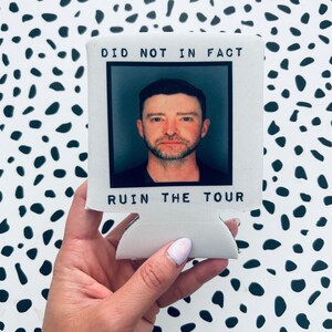 May include: White can cooler with a black and white photo of a man with the text "Did not in fact ruin the tour" printed on it.