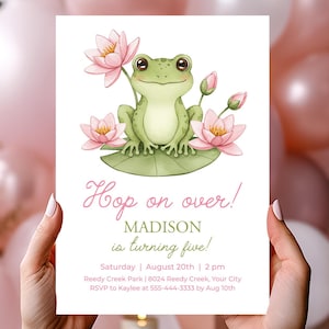 Puede incluir: Una tarjeta de invitación blanca con una ilustración de una rana verde sobre una hoja de nenúfar, rodeada de flores de loto rosas. El texto "Hop on over!" y los detalles del evento están en rosa. Globos rosas y blancos en el fondo.