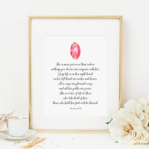 Peut inclure: Une illustration aquarelle d'une pierre précieuse rouge avec une citation de Proverbes 3:15-15. La citation dit : "Elle est plus précieuse que les rubis, rien de ce que tu désires ne peut se comparer à elle. La longue vie est dans sa main droite, dans sa main gauche sont les richesses et l'honneur. Ses voies sont des voies agréables, et tous ses chemins sont la paix. Elle est un arbre de vie pour ceux qui la tiennent, ceux qui la tiennent ferme seront bénis."