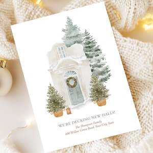 Könnte beinhalten: Eine Weihnachtskarte mit einer Aquarellillustration einer verschneiten Tür, die mit einem Kranz geschmückt und von Topf-Tannenbäumen flankiert wird. Der Text lautet "WE'RE DECKING NEW HALLS!" mit Familienname und Adresse.