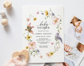 Puede incluir: Una invitación a un baby shower con un diseño de corona de flores, dos pájaros y el texto "baby shower", "Please join us as we honor Amber Johnson", "Saturday, April 27th - 2:00 pm", "The Smith Residence", "234 Oakwood Drive - Your City", "Please respond to Cathy at 555-444-3333" y "Amber is registered at Amazon and Target".