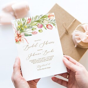 May include: A white bridal shower invitation with a watercolor floral design featuring pink and green flowers. The invitation text reads "Join us for a Bridal Shower honoring Johanna Brooks. Saturday, May 20th, 3 o'clock, 90241 Willow Lane, Your City, State. RSVP to Katie at 555-444-3333. Registered at Pottery Barn & Target."