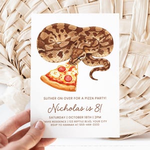 以下が含まれることがあります： 茶色のヘビがピザを食べている水彩イラストが描かれた白い招待状。テキストには「SLITHER ON OVER FOR A PIZZA PARTY!」と「Nicholas is 8!」が表示され、パーティーの詳細も記載されています。