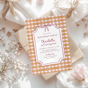 May include: A birthday party invitation with a gingham pattern in shades of orange and pink. The invitation features a decorative frame with the text "Join us for a BIRTHDAY PARTY Charlotte is turning one!" and event details.